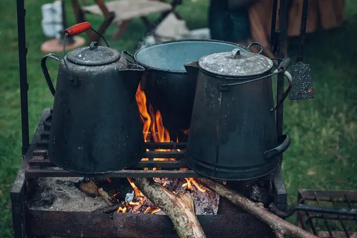 Two Cast Iron Kettles and a Pot over a Campfire